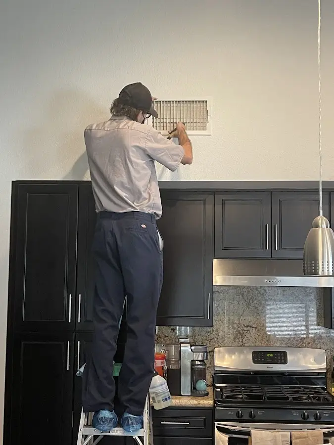 Technician inspecting an air vent during HVAC service in Skiatook